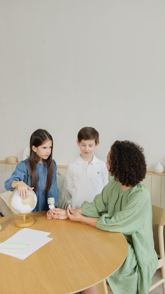 our-experience Kids engaging with a teacher in a lesson on sustainability using a globe and light bulb.