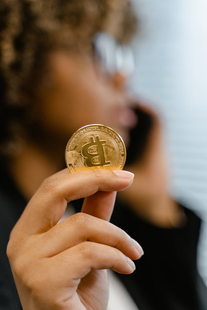 gallery-4 A person holding a Bitcoin coin, symbolizing digital currency and investment.
