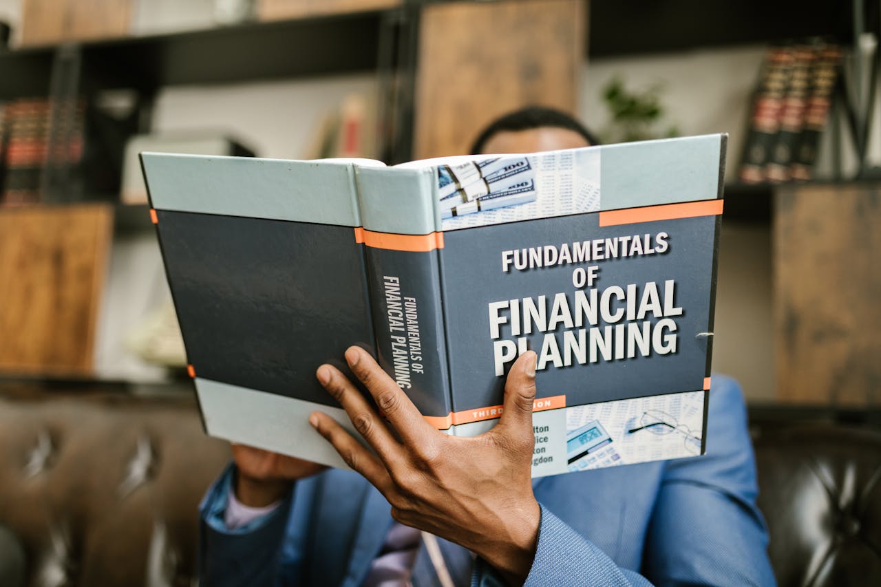 ours-journey A professional individual in a suit reading 'Fundamentals of Financial Planning' indoors.
